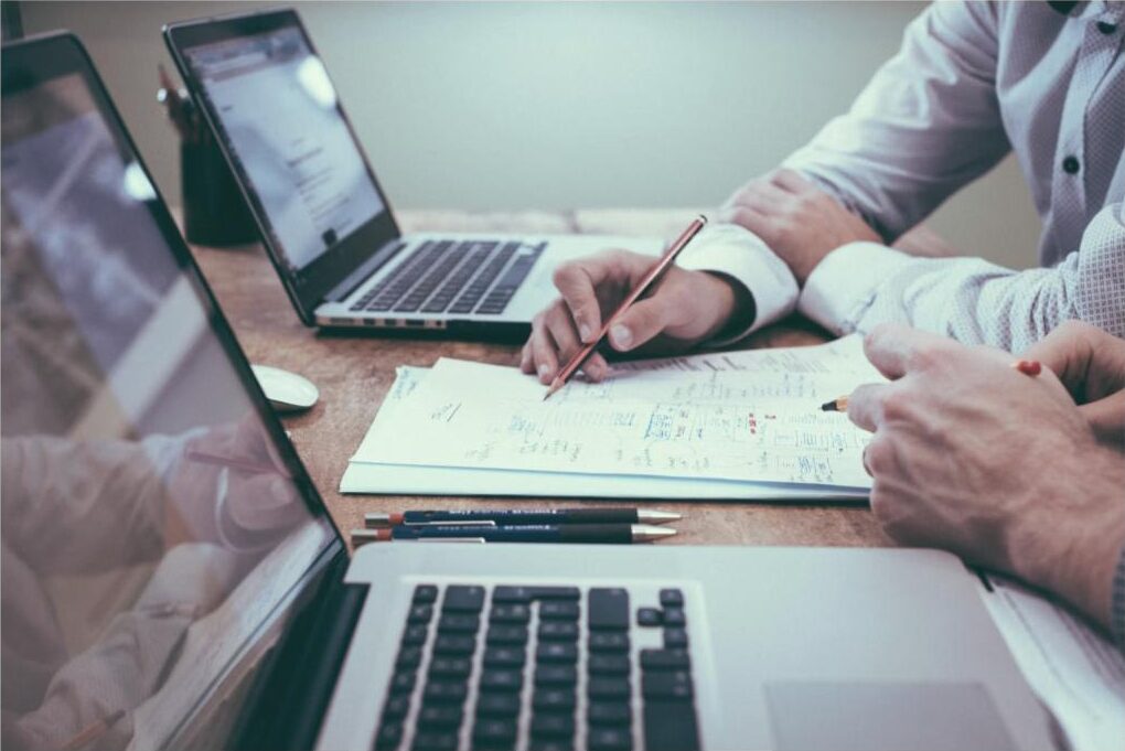 Collega's maken samen notities bij laptops tijdens een overleg